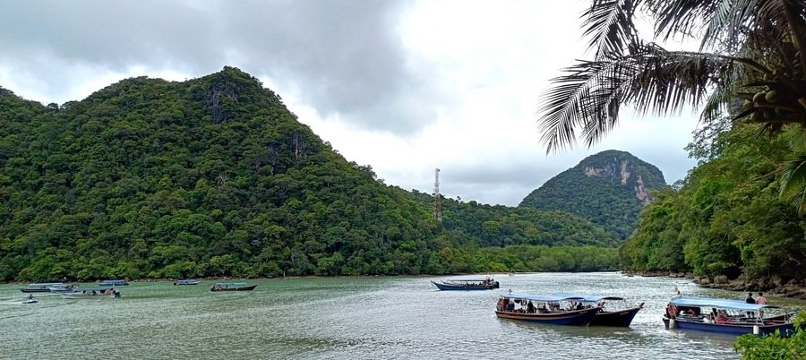 Boats anchored near the lush green hills of the Southern Island Geopark during a Langkawi island hopping tour